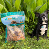 A black and white dog standing next to a Chew Variety Grab Bag (2 lb) of Best Bully Sticks treats.