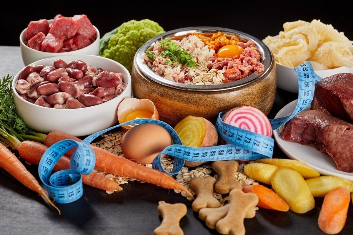 meats, vegetables, and dog bones on a table with a measuring tape