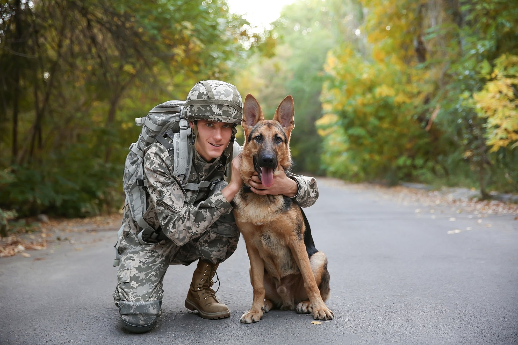 military member posing with dog on a trail