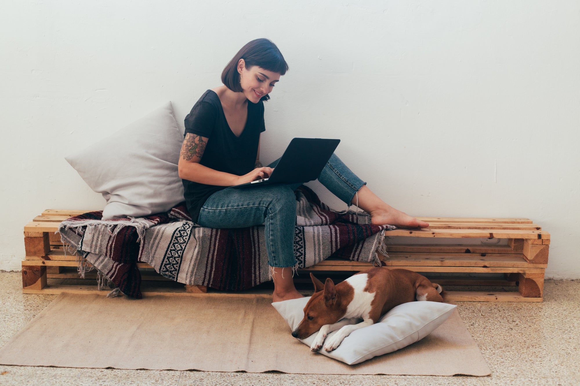 woman sitting with laptop with her dog on the floor