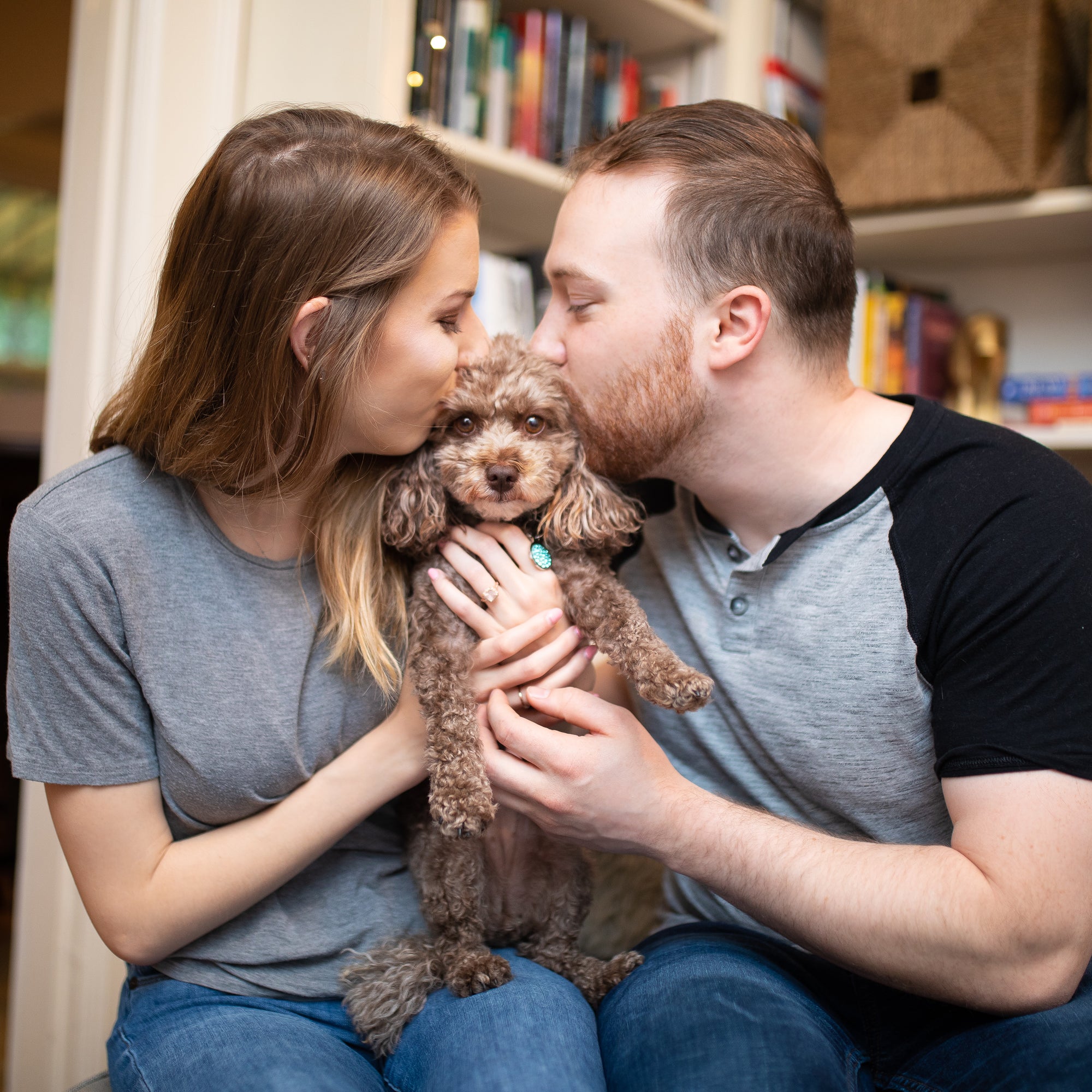 woman and man kissing small poodle