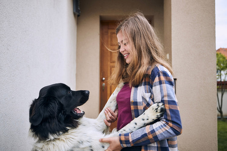 girl coming home to a welcoming dog