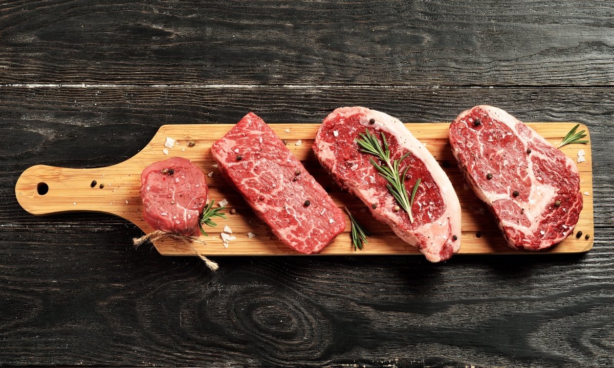 cutting board with 4 steaks on it