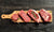 cutting board with 4 steaks on it