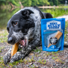 A Best Bully Sticks Hickory Smoked Sampler Box containing a dog happily chewing on a bone alongside a bag of Hickory Smoked dog food.