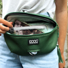A woman is holding a green Best Bully Sticks Neoprene Fanny + Crossbody bag with a cell phone in it.